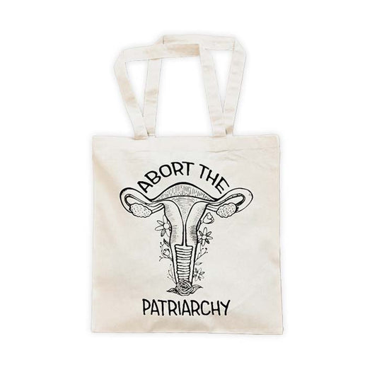 natural canvas tote with a black screen printed floral uterus graphic and "abort the patriarchy" text