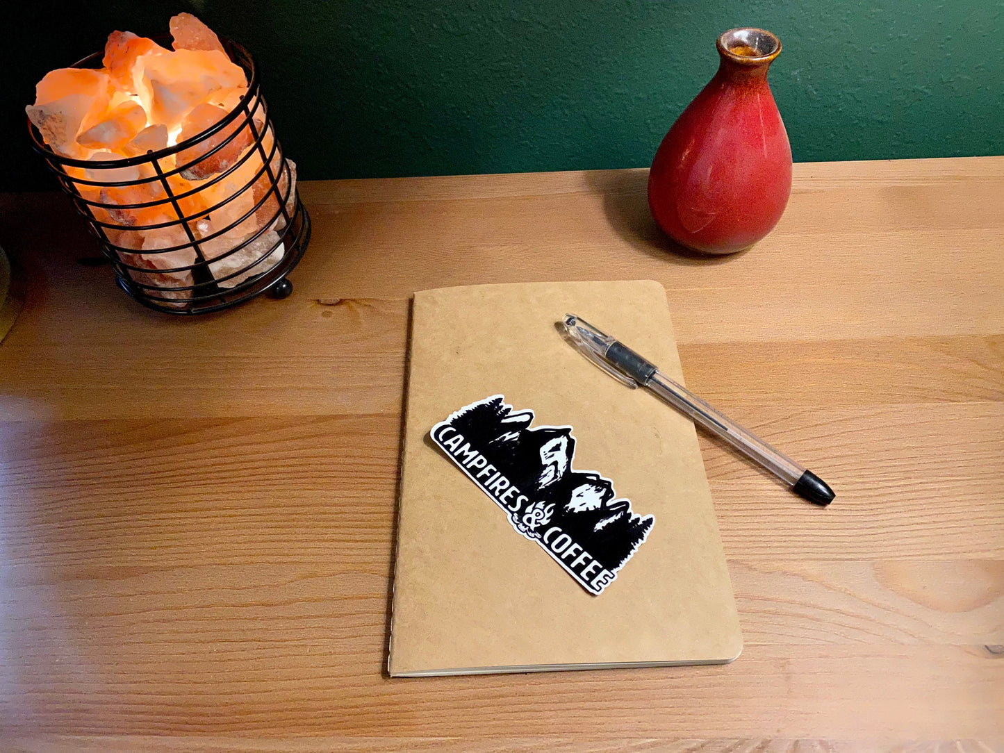 campfires and coffee vinyl sticker displayed on a small kraft notebook